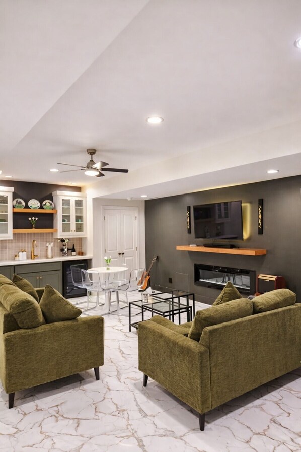 A modern living room with a TV, sofa, and dining area. - Cozy KC Retreat, Private Suite w/ Patio &Fireplace (Kansas City)