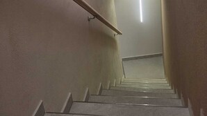 Eine Treppe mit Geländer, einer Lampe oben und einer Tür unten.