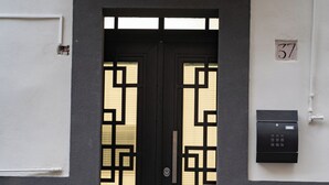 Eine schwarze Tür mit geometrischen Mustern, einem Zahlenschloss und einem Schild mit der Nummer 37 an der Wand.