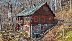 A log cabin with a stone foundation, a porch, and a stone staircase leading up to the entrance. - Welcome to your peaceful 4 Br cabin, minutes from the historic Lake Junaluska. (Waynesville)
