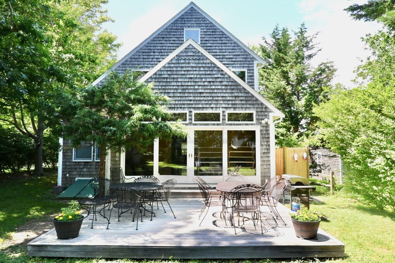 Una casa con terraza, mobiliario exterior y jardín.