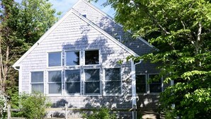Une maison à deux étages, dotée d’un toit à pignon, de nombreuses fenêtres et d’un porche à l’avant.