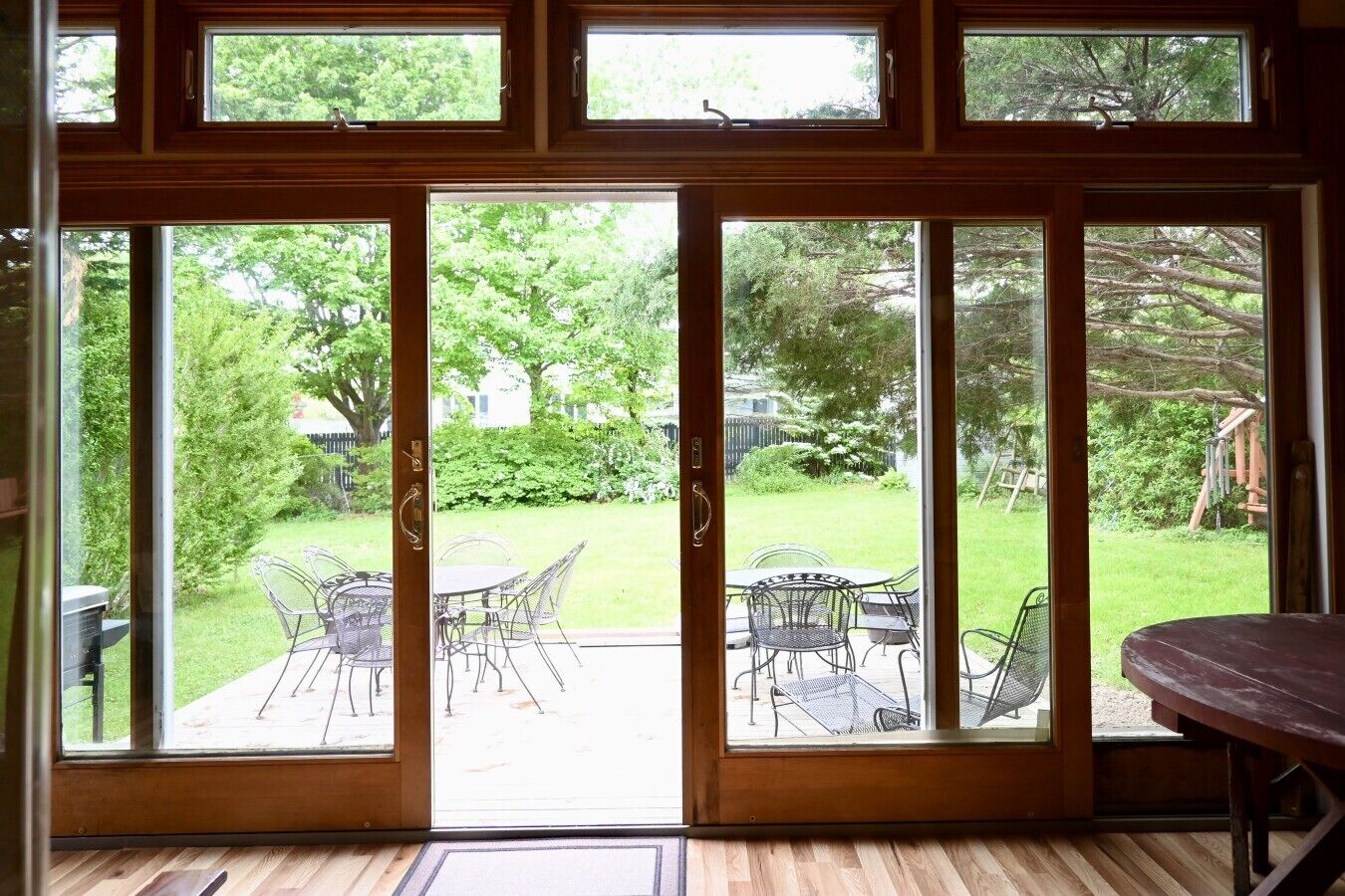 A room with a large sliding glass door leading to an outdoor patio with chairs and a table.