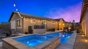 Un jardin avec une piscine, un espace salon extérieur et des guirlandes lumineuses.