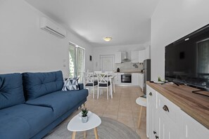 A modern living room with a blue sofa, a TV, and a small white table with a plant. - Apartman Marija Volme, nice apartment with private garden (Banjole)