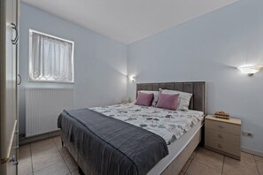A bedroom with a bed, bedside tables, a window with curtains, and a radiator. - Apartman Marija Volme, nice apartment with private garden (Banjole)