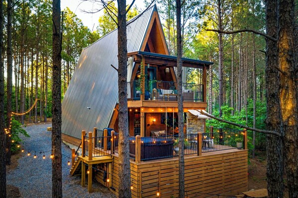Eine Hütte mit geneigtem Dach, einer Holzterrasse und einer Veranda mit Sitzgelegenheit im Freien.