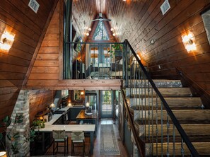 Ein Holzhütten-Innenraum mit Essbereich, Küche und einer Treppe, die zum Schlafzimmer auf dem Loft führt.