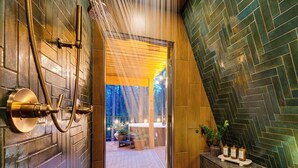 Un baño con ducha, un banco de madera y vistas a un espacio exterior con plantas.