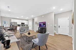 Una sala de estar moderna con un sillón gris, una mesa de centro y un televisor de pantalla plana.
