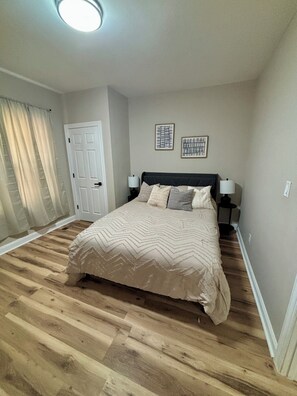 Ein Schlafzimmer mit einem Bett, zwei Nachttischen, einer Tür und zwei Wandleuchten.