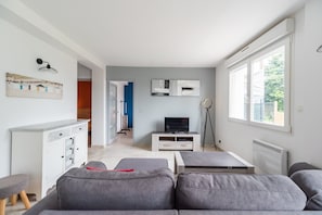 Ein modernes Wohnzimmer mit einer Couch, einem Fernseher und einer Ringleuchte.