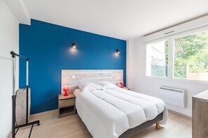 Ein Schlafzimmer mit einem Bett, Nachttischen, einer Wandlampe, einem Fenster mit Blick und einer Heizung.