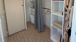 Walk-in-garderobe med åbne hylder, ophængningsplads og en dør.