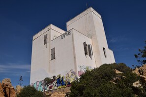 Ein hohes, weißes Gebäude mit Graffiti an der Fassade und einem strahlend blauen Himmel im Hintergrund.