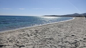 A beach with clear skies, a sandy shore, and a mountain in the distance. - Suite Ibisco 3 -LE Dimore Fiorite DI Comino (Siniscola)