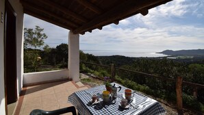 A terrace with a checkered tablecloth, a chair, and a table set with cups, a teapot, and a pitcher. - Suite Lavanda 2 - LE Dimore Fiorite DI Comino (Siniscola)
