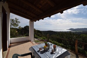 A terrace with a checkered tablecloth, a table set with cups, a teapot, and a potted plant. - Suite Mimosa 4 - LE Dimore Fiorite DI Comino (Siniscola)