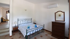 A bedroom with a bed, bedside tables, a dresser, an air conditioning unit, and a mirror. - RES Magnolia 9 - LE Dimore Fiorite DI Comino (Siniscola)