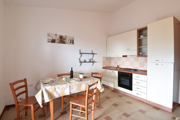 Eine kleine Küche mit Esstisch, Stühlen, Herd und Kühlschrank.