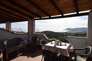 Ein überdachter Außenbereich mit Tisch und Stühlen, mit Blick auf eine malerische Landschaft.