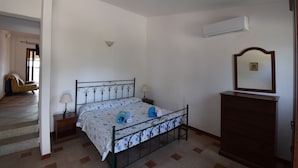 Un dormitorio con cama, mesitas de noche, cómoda, espejo y equipo de aire acondicionado.