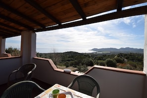 Ein Balkon mit Tisch, Stühlen und Blick auf Meer und Berge.