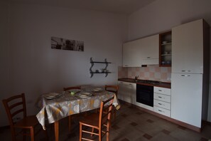 Eine kleine Küche mit Esstisch, Stühlen, Herd und weißen Schränken.