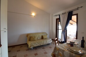 Ein Zimmer mit einer Couch, einem Esstisch mit einer Flasche, Tellern und einem Stuhl.