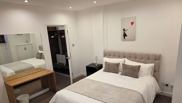 A bedroom with a bed, bedside table, bench, and a mirror. - Boutique Dairy Conversion Near Ilford Station (Ilford)