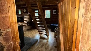 Een houten interieur met een stenen muur, een trap en een bank.
