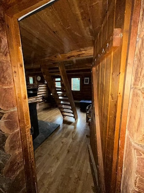 Un interior de madera con pared de piedra, una escalera y un banco.