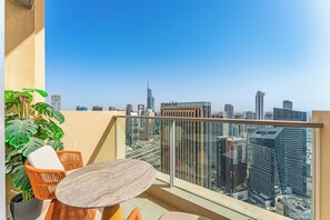 Ein Balkon mit Tisch und Stühlen, einer Topfpflanze und Blick auf die Stadt.