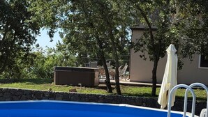 En swimmingpool med en mur av sten, utomhusmöbler och träd.