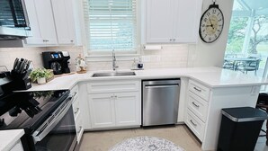 A modern kitchen with white cabinets, a stainless steel dishwasher, a built-in oven, and a round rug. - Lake Access-Boat Parking- 2 King Beds-Sleeps 10 (Eufaula)