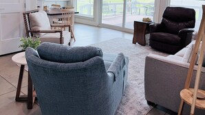 A spacious living room with a ceiling fan, large windows, and a view of the outdoors. - Lake Access-Boat Parking- 2 King Beds-Sleeps 10 (Eufaula)