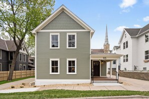 A two-story house with a gabled roof, a front porch, and a visible address number.
