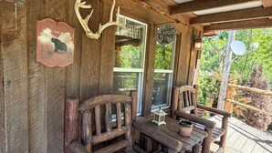 A wooden porch with rustic furniture, a bear sign, and a cabin sign. - Cozy 1-bedroom cabin in perfect Wathena with AC (Wathena)
