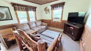 A cozy living room with a sofa, a wooden coffee table, a television, and a fireplace. - Cozy 1-bedroom cabin in perfect Wathena with AC (Wathena)