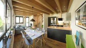Eine moderne Küche mit Essbereich, Holzbalken und einem großen Fenster.