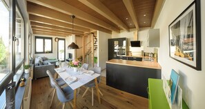 Eine moderne Küche mit Essbereich, Holzbalken und einem großen Fenster.