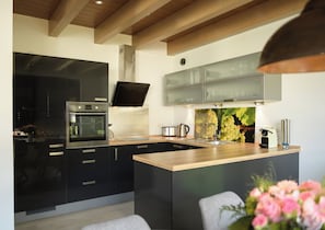 Una cocina moderna con gabinetes negros, electrodomésticos de acero inoxidable y una isla de madera.
