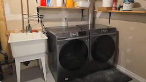 Un espace buanderie comprenant un lave-linge, un évier et une petite table.