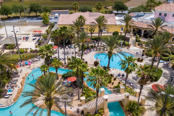 Ein Resort mit einem zentralen Pool, Palmen und einem Gebäude mit rotem Ziegeldach.