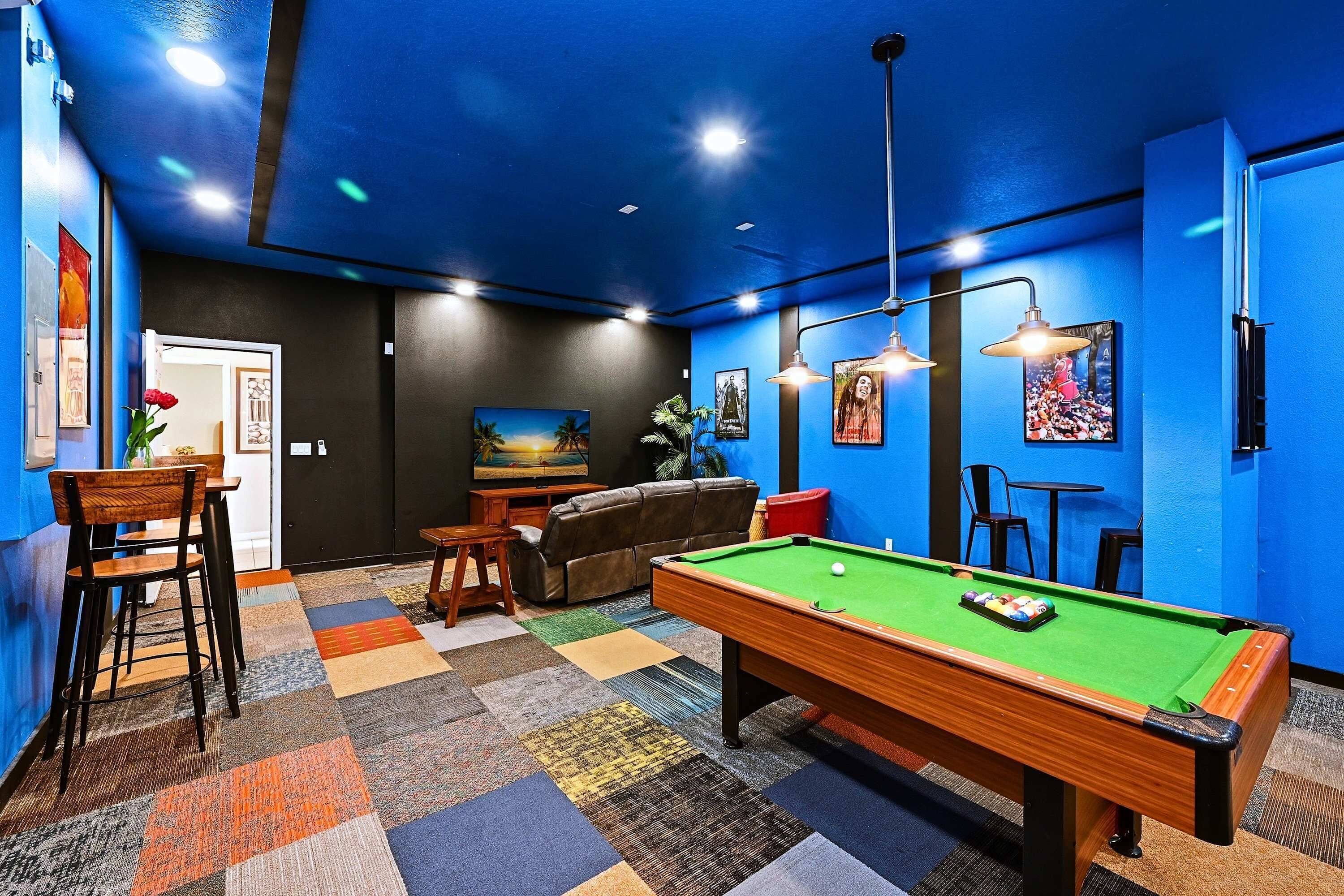 Ein Billardtisch in einem Raum mit blauen Wänden, einer Couch und einem kleinen Tisch mit Stühlen.