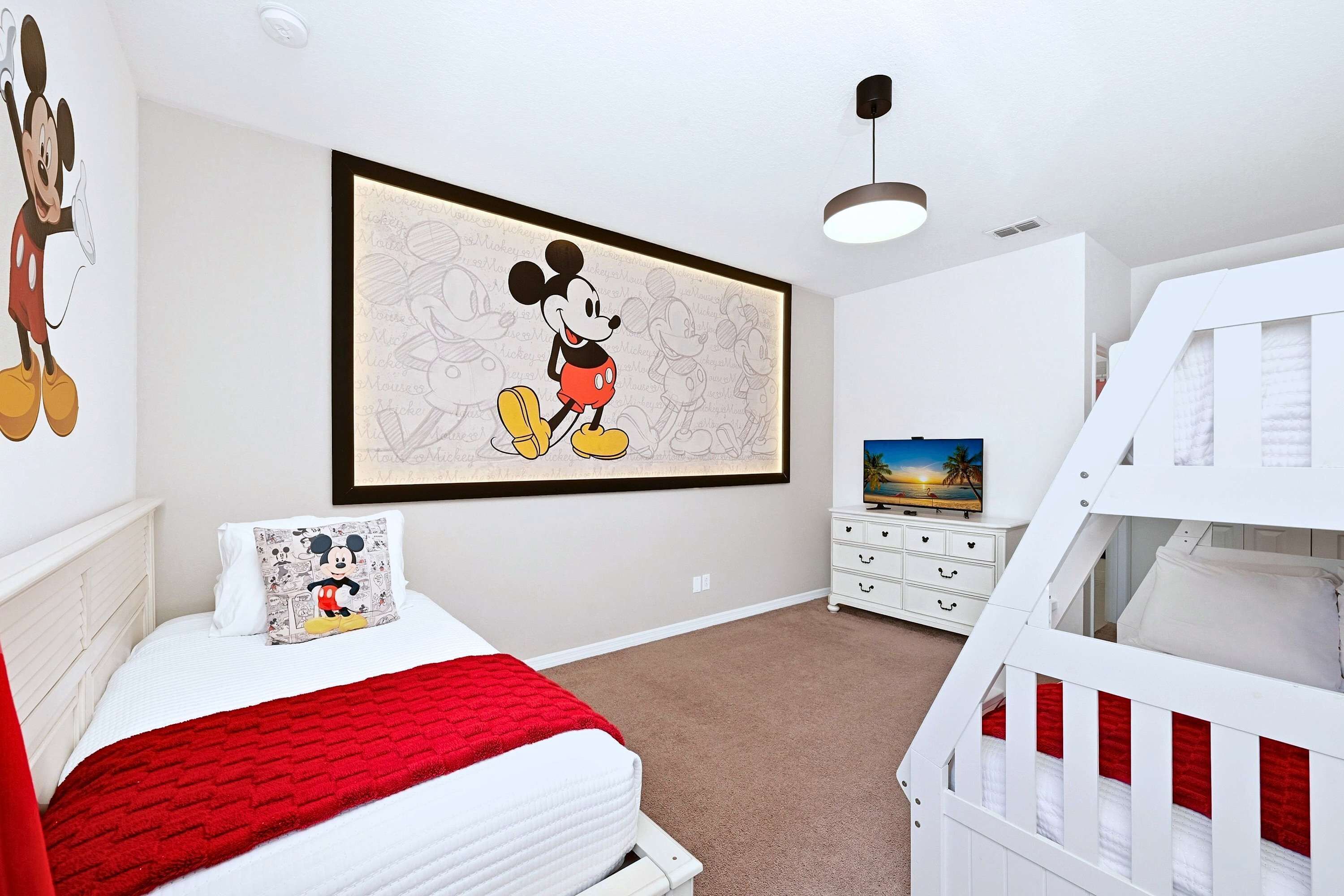 Une chambre d’enfant avec un lit, un berceau, une décoration murale, une commode et un téléviseur.