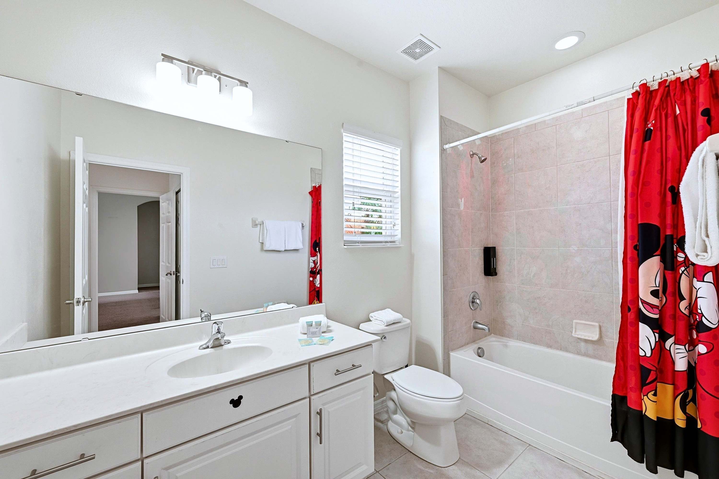 A bathroom with a white sink, mirror, toilet, and shower curtain.