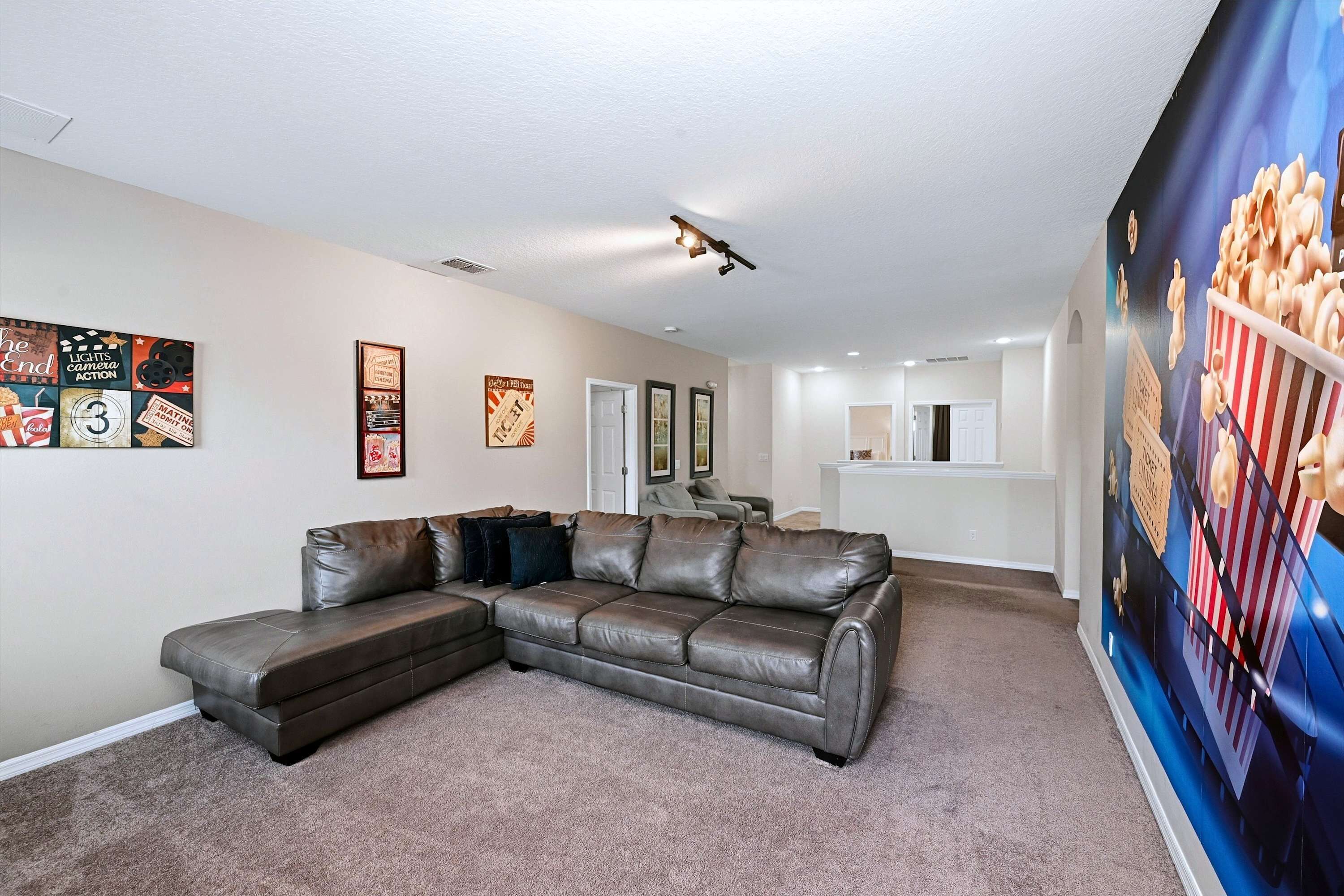 A living room with a sectional sofa, a popcorn-themed wall mural, and a ceiling light fixture.