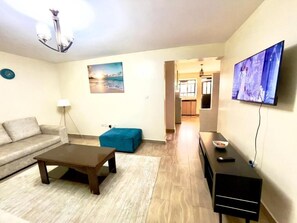 Ein Wohnzimmer mit einer Couch, einem Couchtisch, einem Fernseher und einem Gemälde an der Wand.