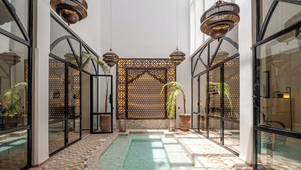 A pool area with a patterned floor, glass walls, and hanging lamps. - Expérience Riad privé Médina Jacuzzi (Marrakech)